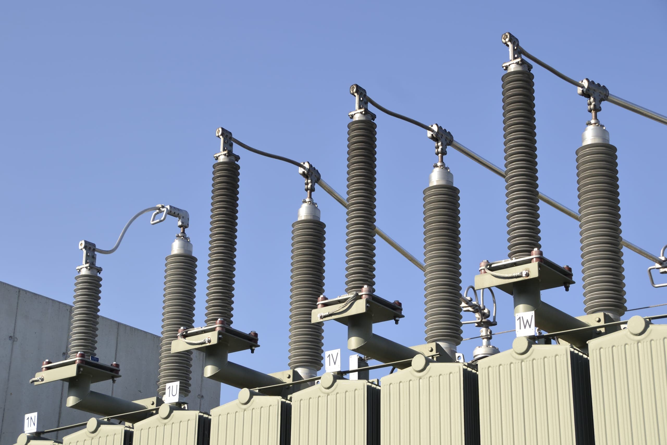 Row of high-voltage bushings on top of power transformers
